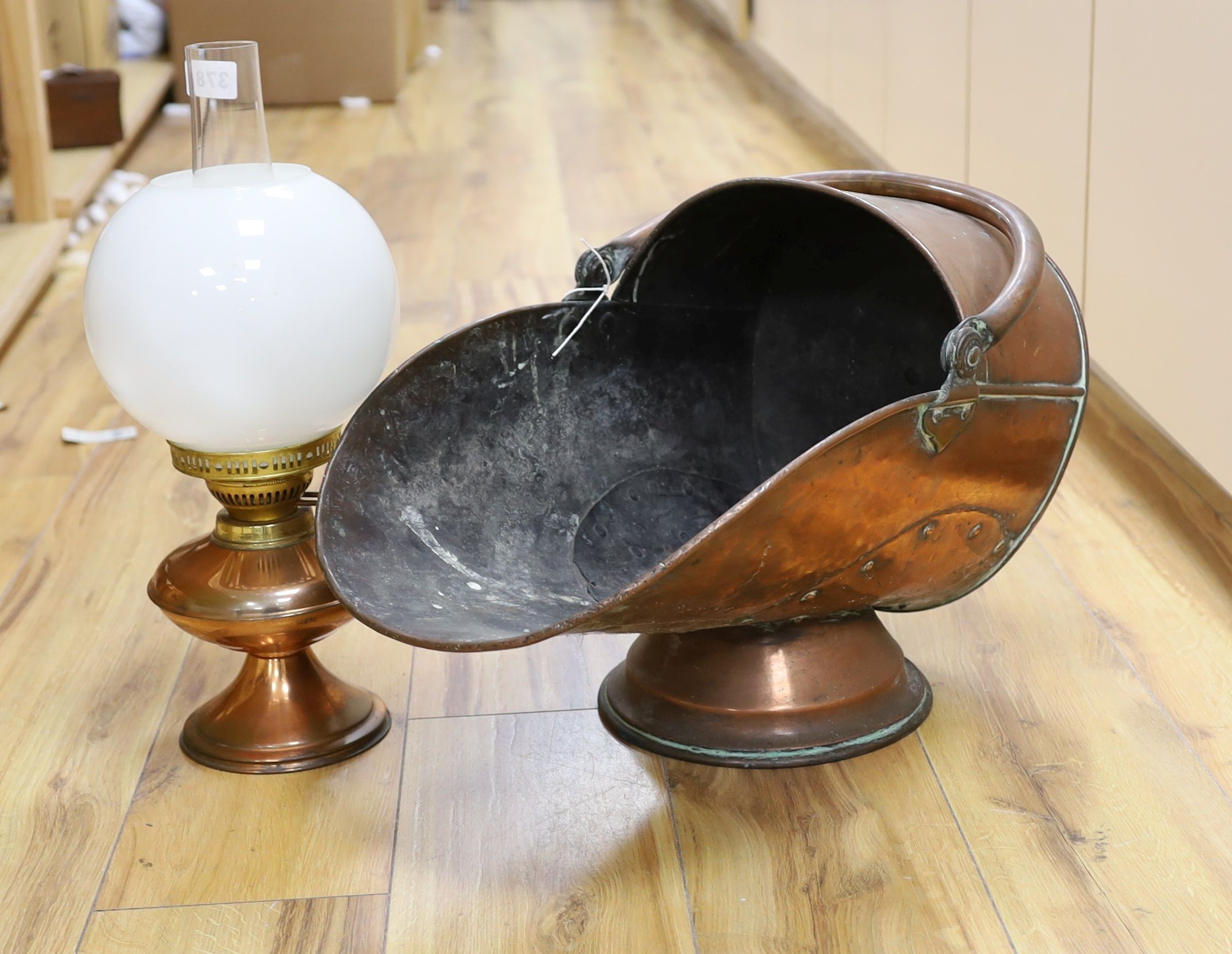 A Victorian copper coal scuttle and a lamp